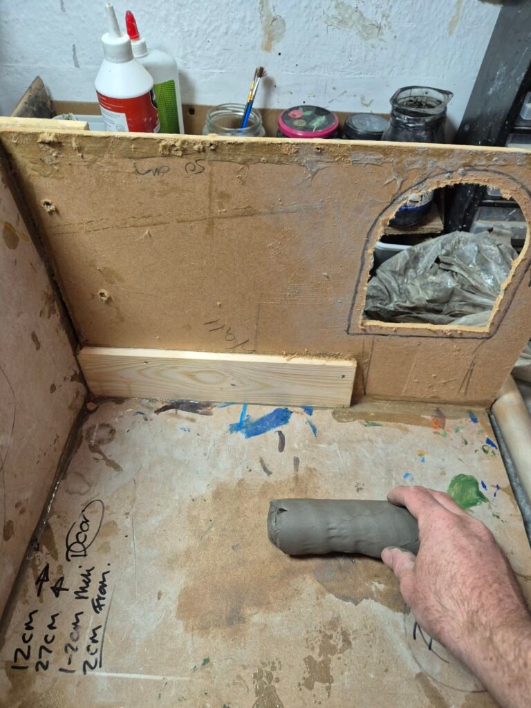 A wooden MDF base for the blacksmith project. Unpainted in a L shape.